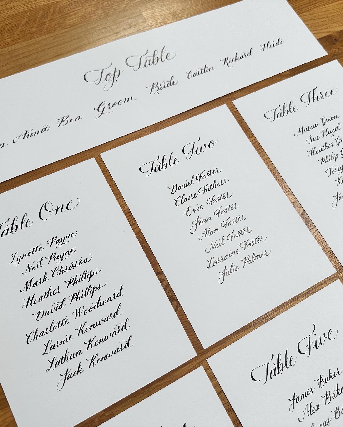 Handwritten seating chart lists beside table name cards on wood